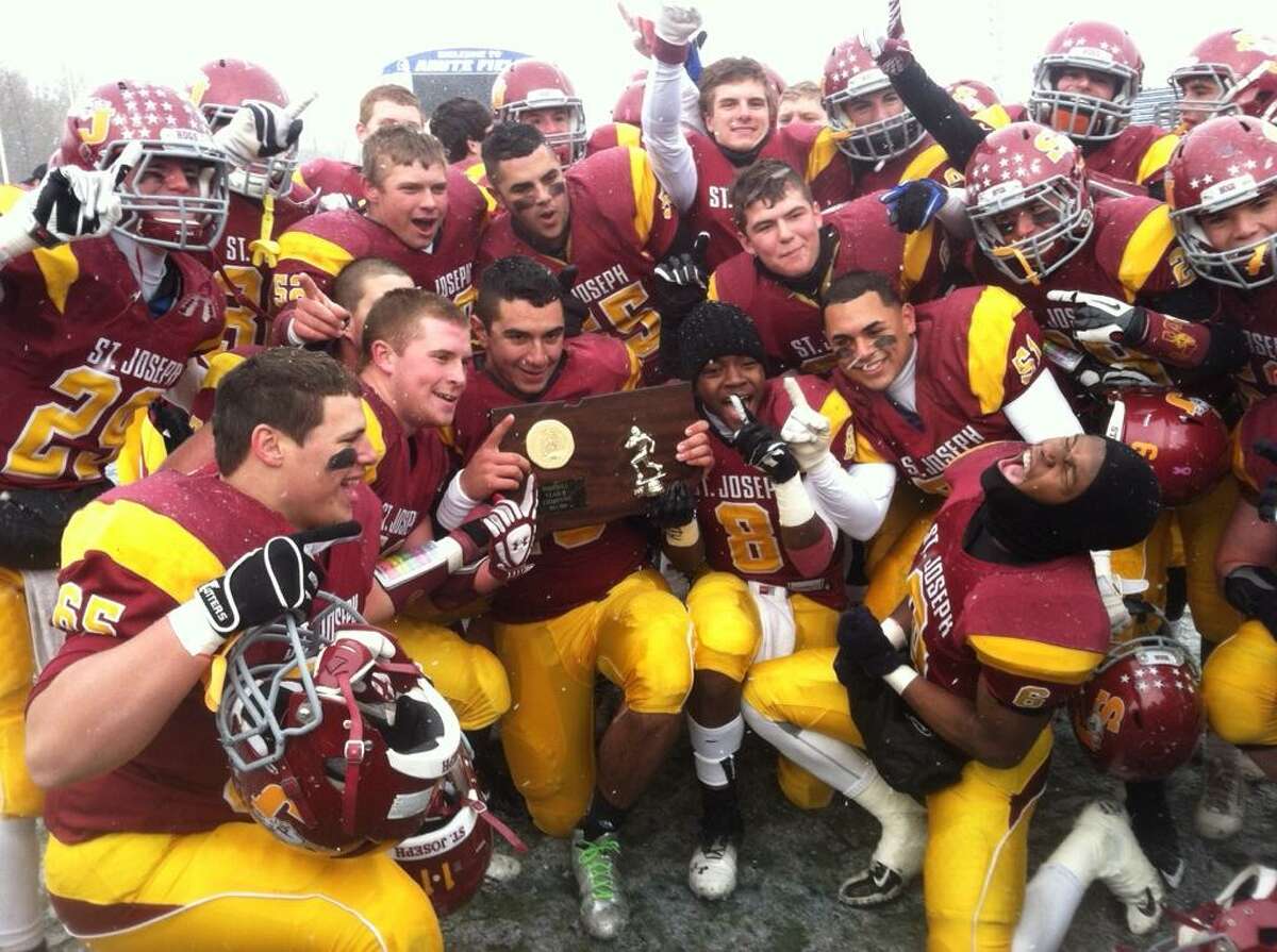 St. Joseph’s players celebrate with the Class M championship trophy after a 54-16 victory over Brookfield at New Britain. Photo by Sean Patrick Bowley