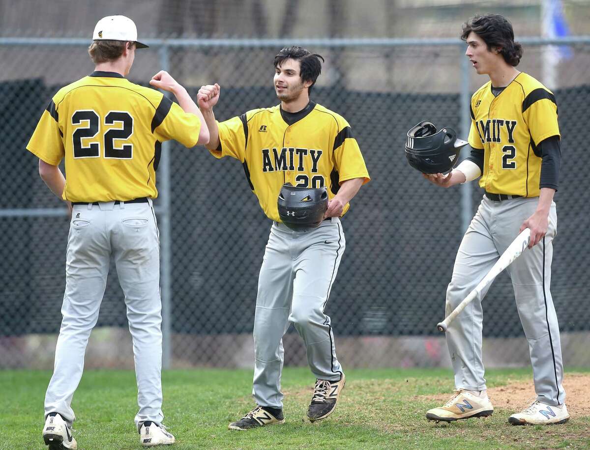 John Nolan (left) of Amity congratulates Jared Smith (center) after his second home run against Shelton in Woodbridge on April 30, 2018. At right is Sebastian Formica.