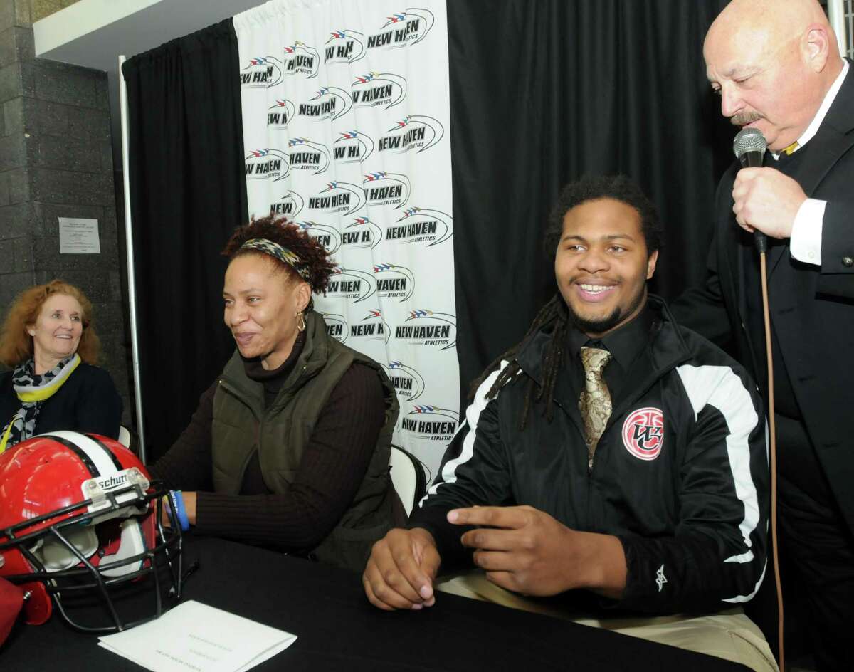 From left: Rebecca Hastings, Tyra Robinson and her football player son Jaelin who will be going to Temple, and supervisor of New Haven athletics Joe Canzanella. (Mara Lavitt — New Haven Register)