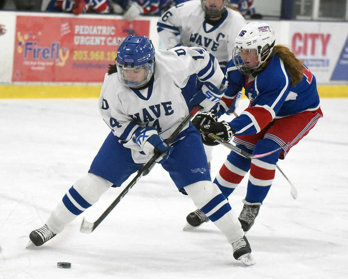 Darien’s Caitlin Chan (14) skates into the zone while West Haven/SHA’s Mackenzie Gardner (16) defends.
