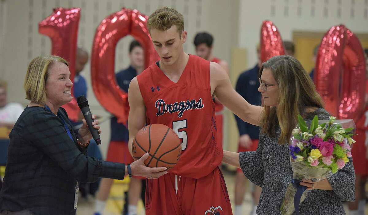 Greens Farms Academy senior Cole Prowitt-Smith, center, is awarded the game ball from athletic director Tauni Butterfield, left, during a ceremony honoring the 1,000-point career scorer at the Coyle Gym in Westport on Tuesday night. At right is Prowitt-Smith’s mother, Lynn.