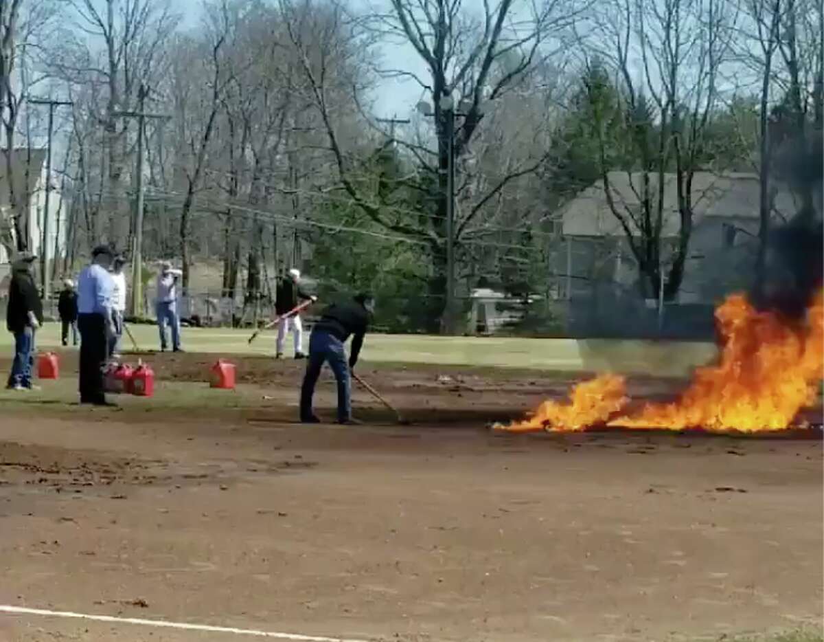 Unidentified people tend to a blaze on Ridgefield's Ciuccoli Field on Saturday afternoon April 8, 2019. before Ridgefield High School was set to play Amity in a baseball game. Police are still investigating the reason and responsible parties involved, which the town says will cost an estimated $50,000 to clean up. The game was moved to Amity's field in Woodbridge by the afternoon. Ridgefield won, 5-4.