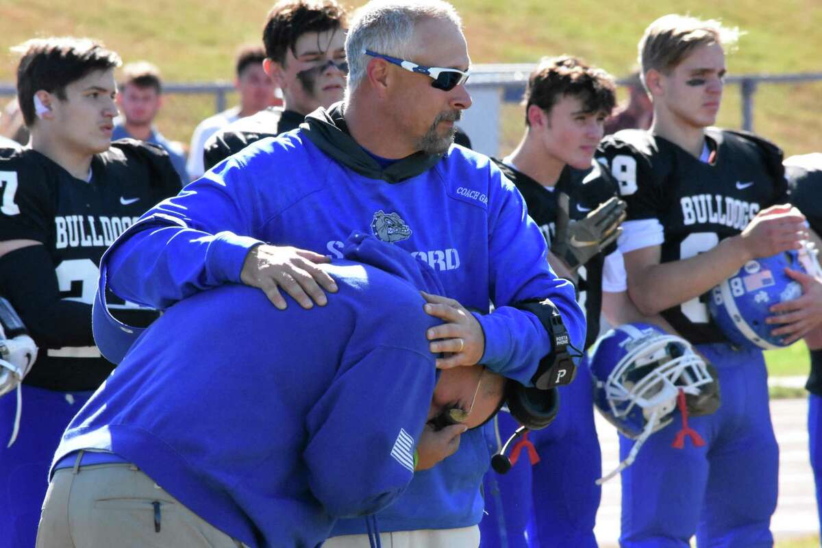 An emotional Stafford/East Windsor/Somers coach Brian Mazzone is consoled by assisant coach Bob Grant before the game at Stafford high school on Saturday, Oct. 5, 2019. (Pete Paguaga, Hearst Connecticut Media)