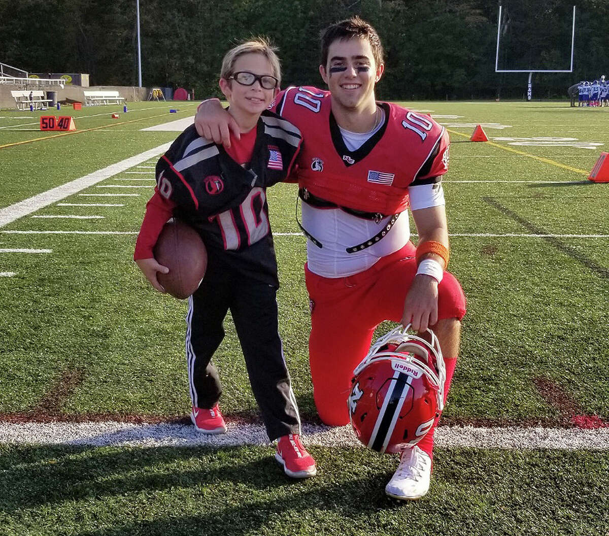 Ryan Berg, 8, and New Canaan senior Drew Pyne at Dunning Field for the Rams’ homecoming football game on Saturday, Oct. 26, 2019.