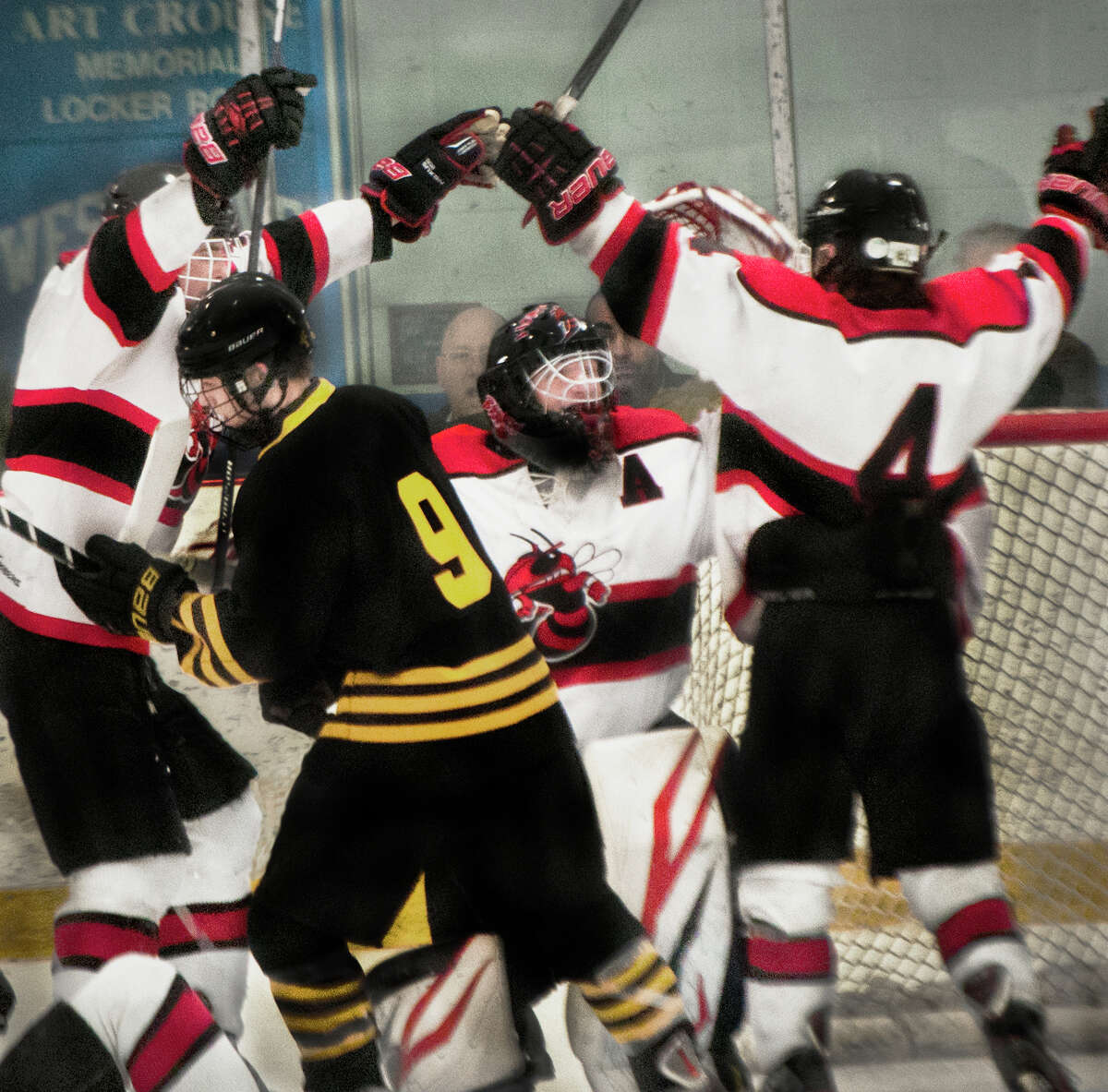 Branford celebrates  with goalie A.J. Brink after its 4-3 victory over Amity in the SCC /SWC Division II hockey championship (Photo Melanie Stengel)