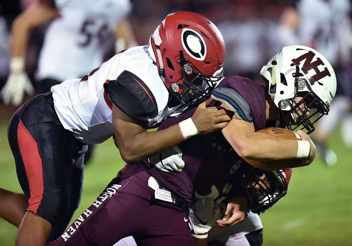 North Haven senior runningback Nick Dodge is tackledt by Cheshire sophomore defensive lineman Chisom Okoro (64) and senior captain Elijah Allston (24) Friday, September 21, 2018, at Vanacore Field at North Haven High School. North Haven won, 34-21.