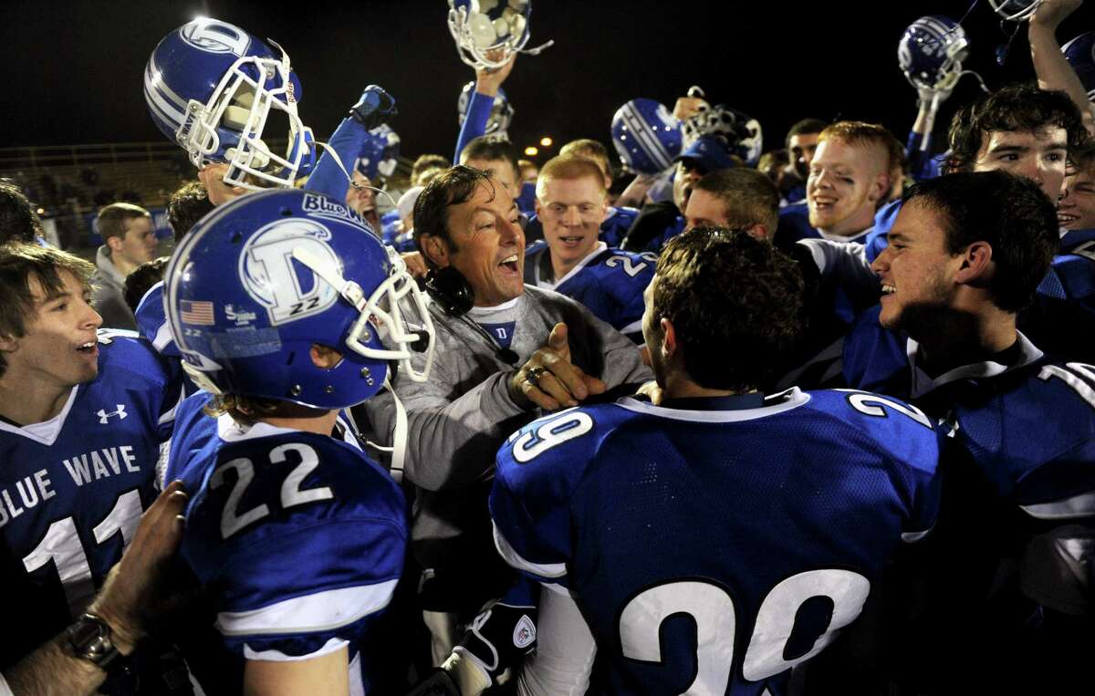 The Darien football team surrounds coach Rob Trifone, center, while celebrating its 17-7 win at Trumbull in the FCIAC game Friday night.