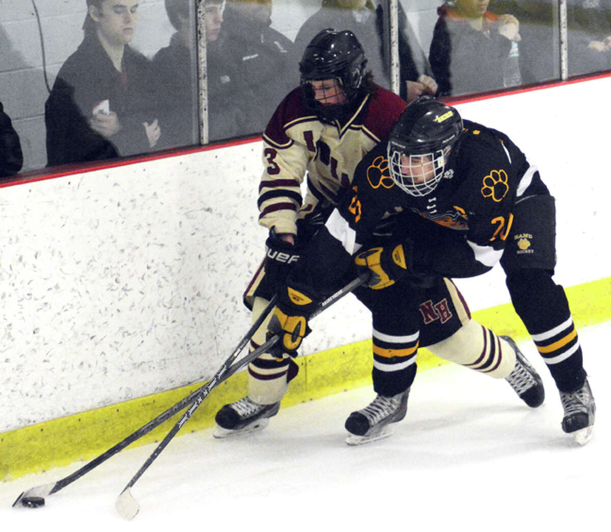 Photo by Dave Phillips/ North Haven’s Tyler Luedee and Hand’s Dan Healey battle for the puck along the boards during the Tigers’ 4-2 victory Friday night at the Northford Ice Pavilion.