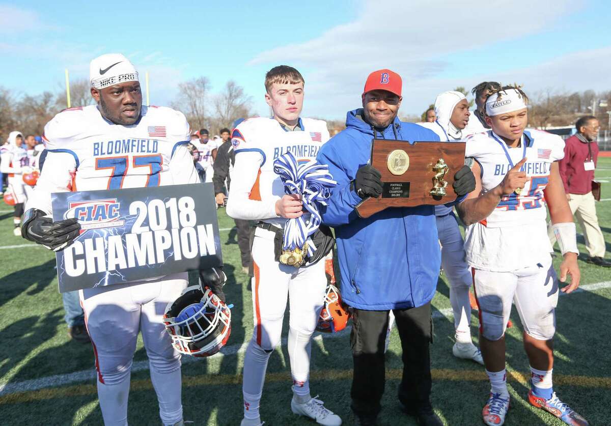 Bloomfield High School football head coach Tylon Outlaw receives the championship plaque with, from left, Chesaih Hill-Gore, Daron Bryden, and Ky’Juon Butler after the Class S Championship Game in New Britain over Haddam-Killingworth High School on Saturday, Dec. 8, 2018.