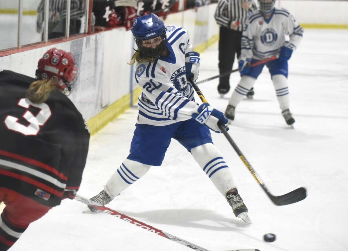 Darien’s Nelle Kniffin (20) takes a shot while New Canaan’s Courtney O’Connell (3) defends during the FCIAC girls ice hockey championship game at the Darien Ice House on Saturday, March 20, 2021.