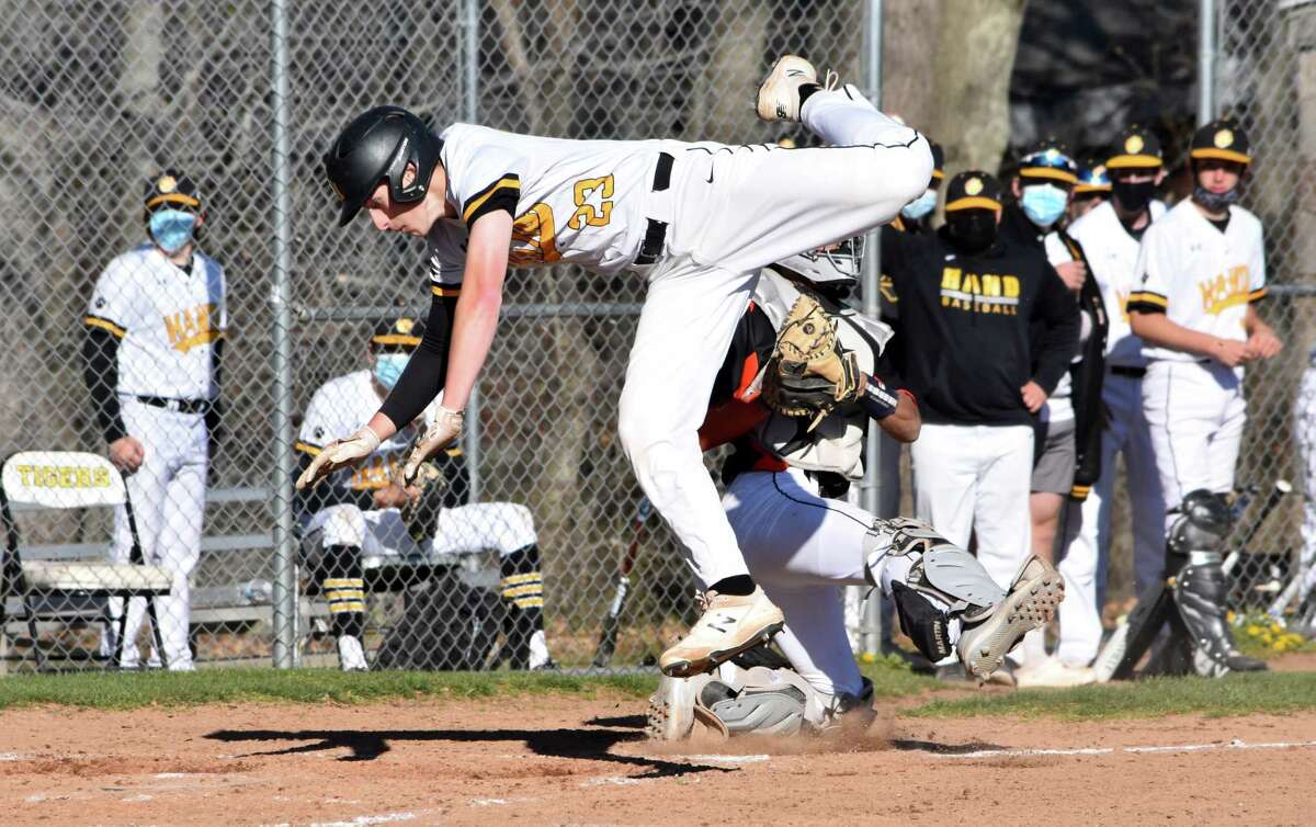 Hand's Connor Powell touches home plate after trying to jump over Shelton catcher Nick Piscioniere. Powell was originally ruled safe, before being ruled out after the umpires talked it over in a baseball game at Hand high school on Monday, April 26, 2021.