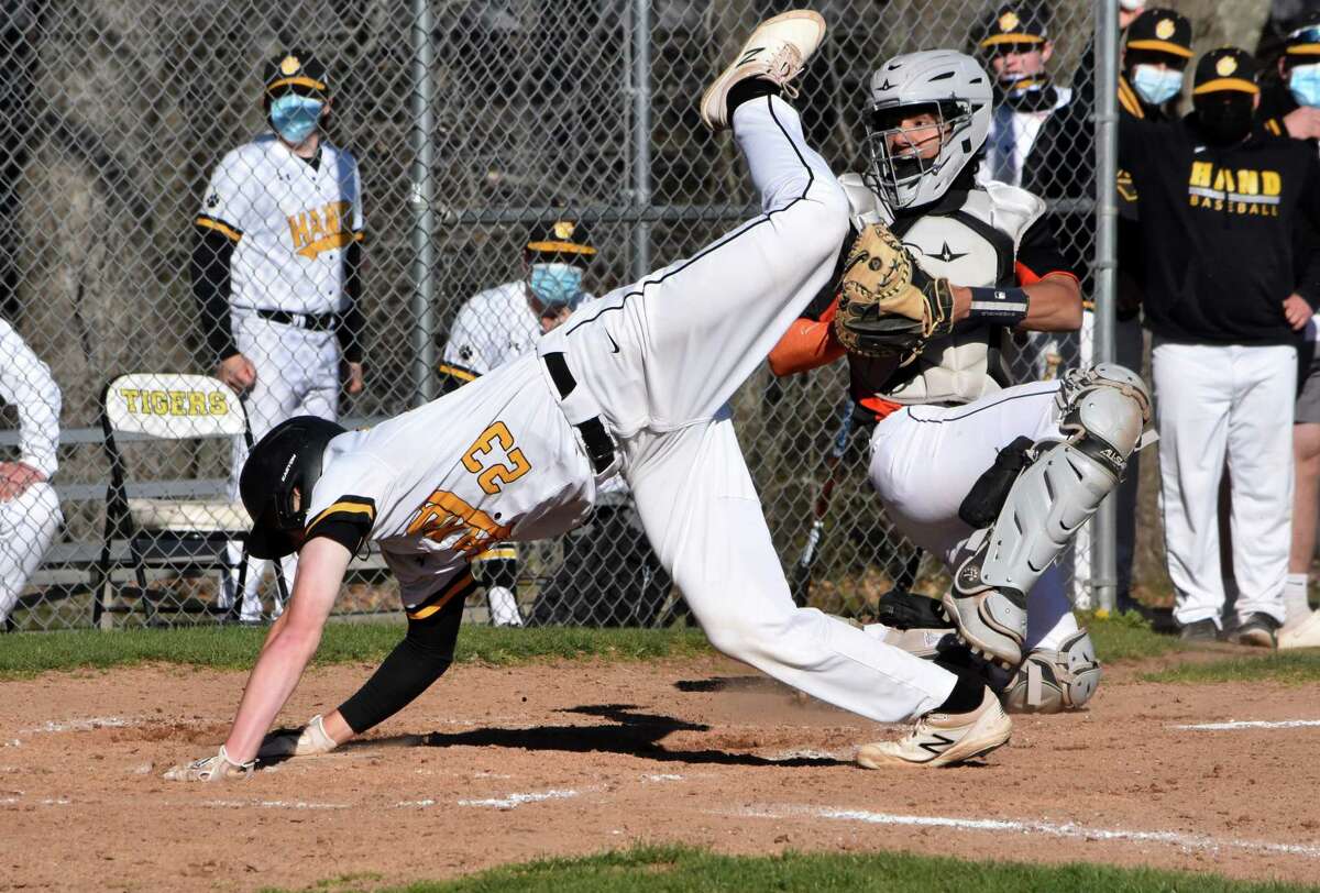 Hand's Connor Powell touches home plate after trying to jump over Shelton catcher Nick Piscioniere. Powell was originally ruled safe, before being ruled out after the umpires talked it over in a baseball game at Hand high school on Monday, April 26, 2021.
