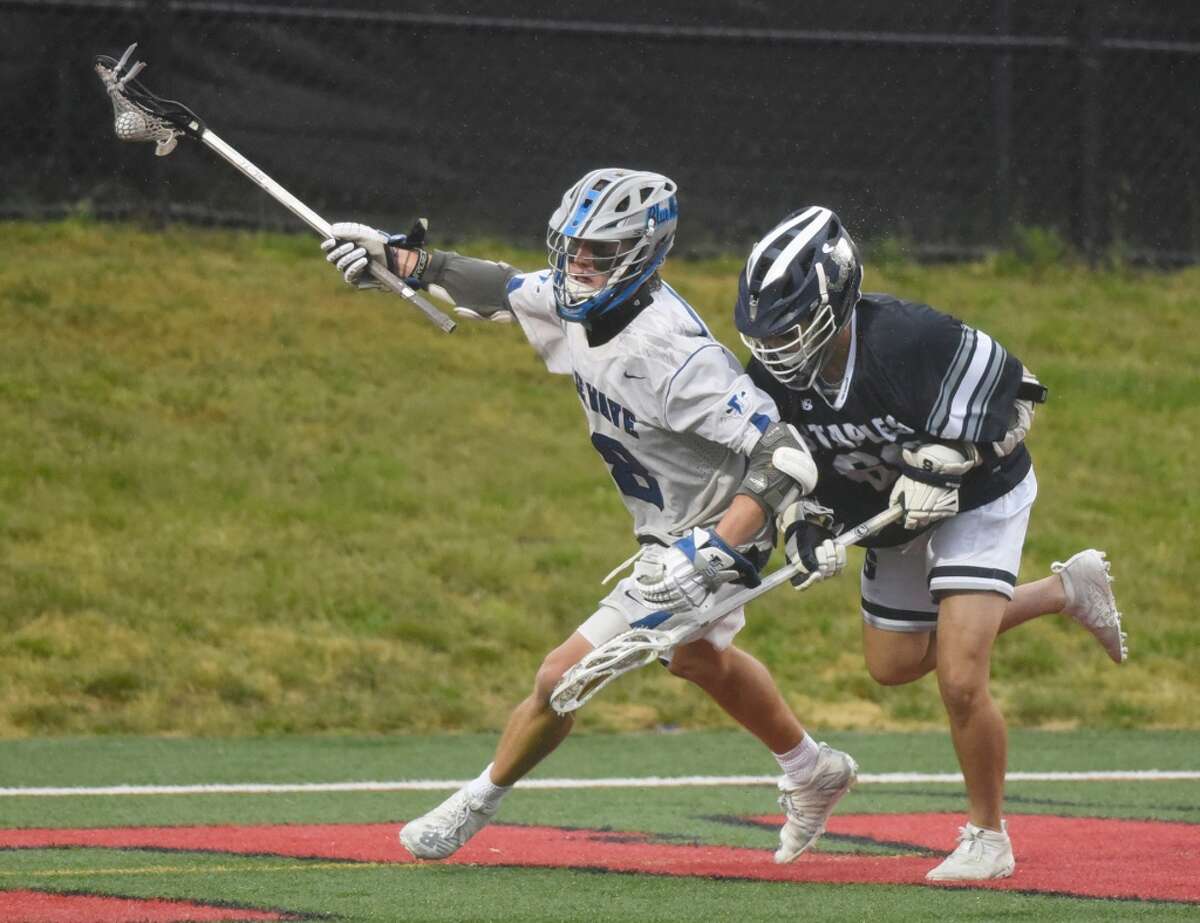 Darien’s Finn Pokorny (18) scoops up and controls the ball while Staples’ Guy Harizman (66) defends during the FCIAC boys lacrosse final at Dunning Field in New Canaan on Friday, May 28, 2021.