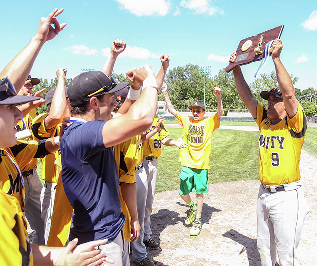 Amity Spartan head baseball coach Sal Copola hoists the State champion plaque for his team to see after Amity defeated Southington 9-2 Sunday at Plamer Field in Middletown. Photo John Vanacore