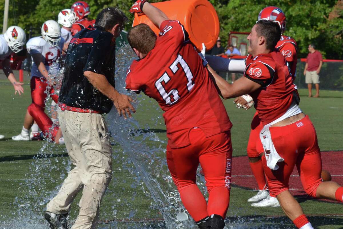 New Canaan’s Jim Keneally (67) and Alex LoPolice (7) pour water on head coach Lou Marinelli after the Rams defeated Greenwich, 35-20 for Marinelli’s 300th career win. Pete Paguaga – New Haven Register
