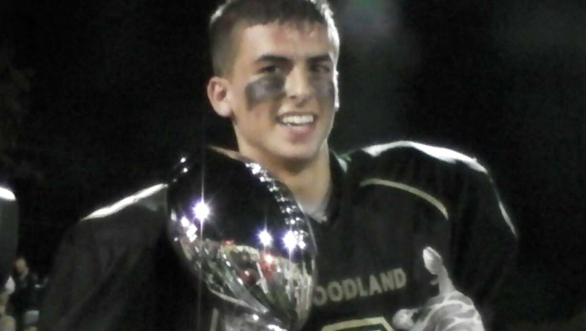 Woodland’s Jack Pinho holds the George Pinho memorial trophy after the Hawks’ 25-22 victory Friday, Oct. 4, 2013