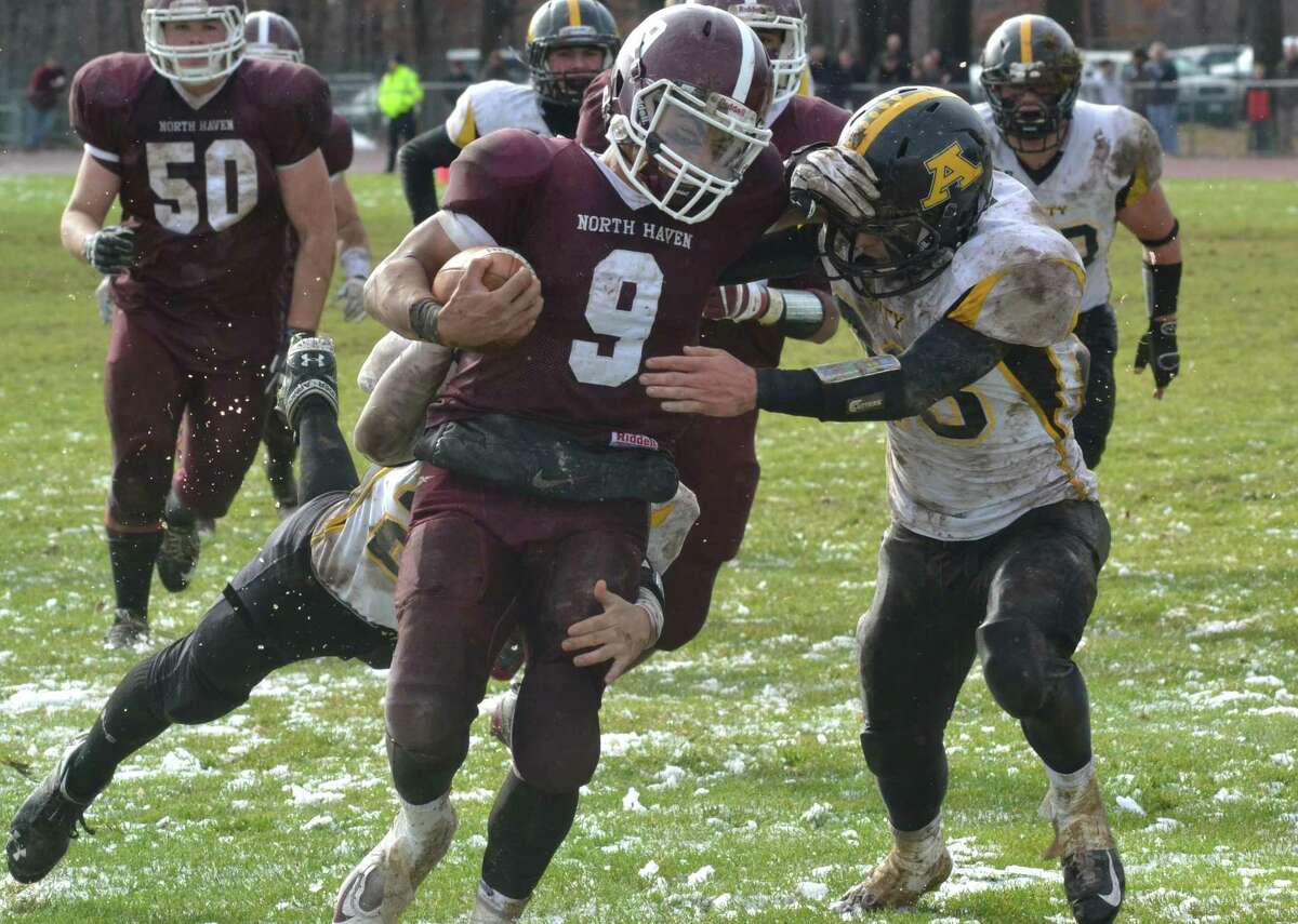 North Haven’s Cole Pecora stiff arms an Amity defender in the Indians 40-20 win over Amity. (Pete Paguaga – Register)