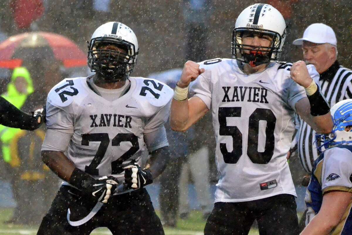 Xavier’s Chidi Broderick and Colin Morris celebrate after sacking Newtown quarterback Jacob Burden in Xavier’s 13-7 win over Newtown. (Pete Paguaga – Register)