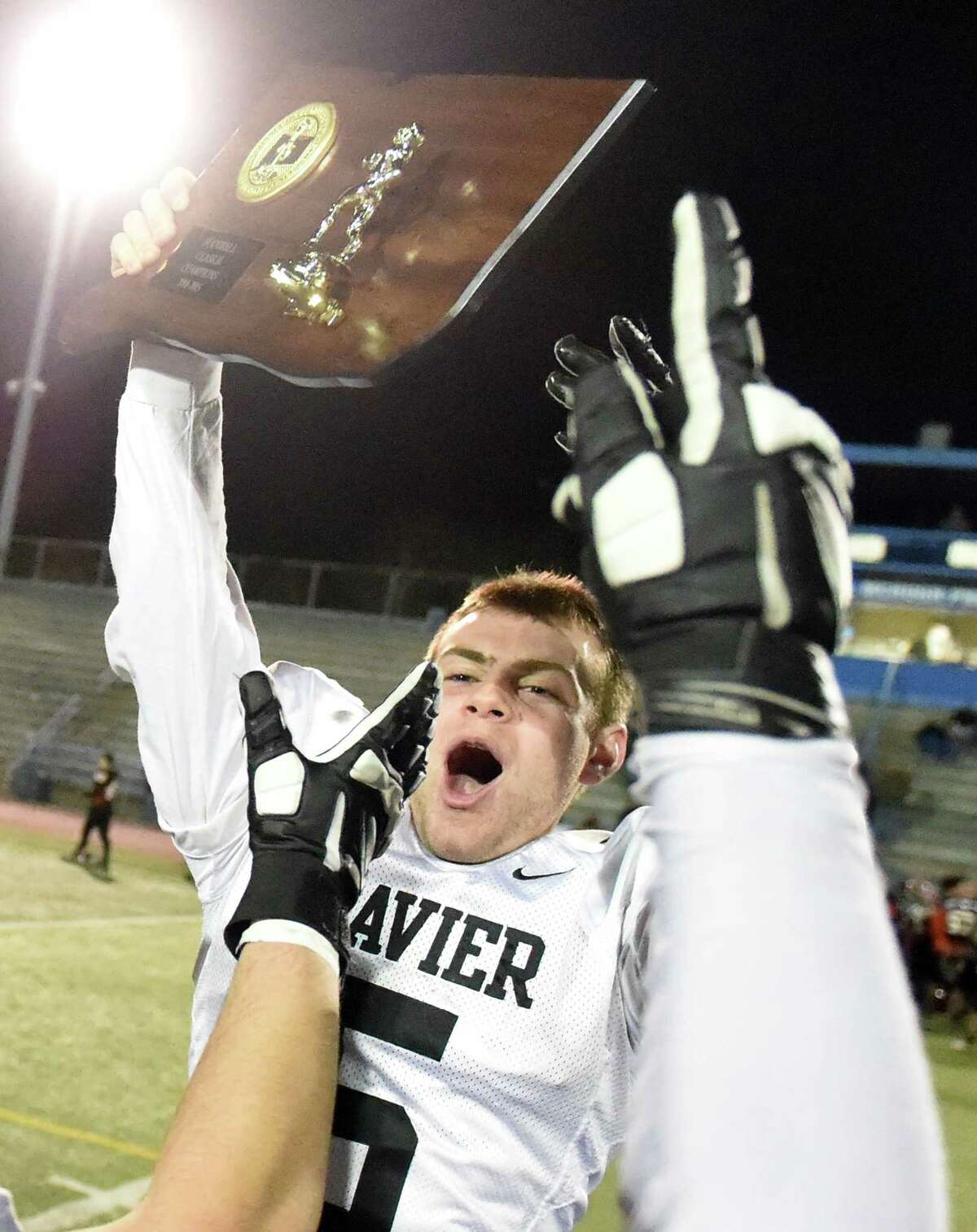 Michael Scherer holds the championship plaque after Xavier came from behind to stun second-seeded and previously unbeaten Shelton, 28-27 in the CIAC Class LL-Small final. (Photo Peter Hvizdak)