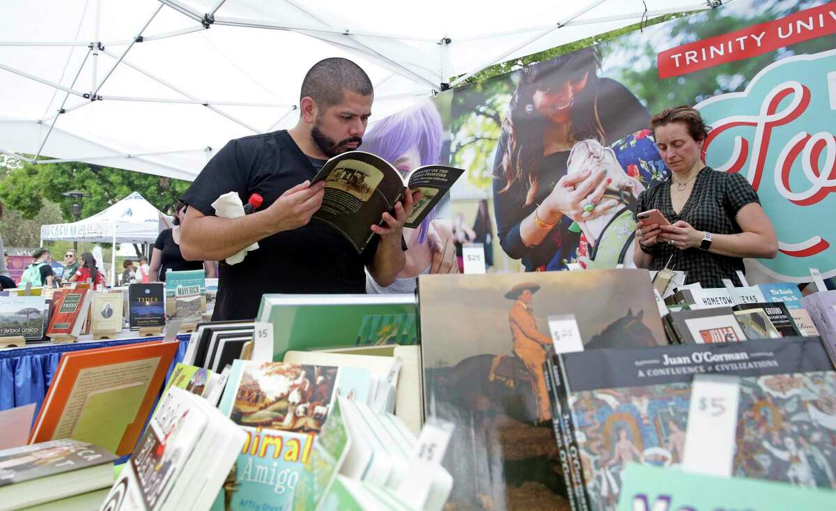 Carlos Lara is absorbed in a history reference book in the Trinity University Press booth during the 7th Annual San Antonio Book Festival in 2019. Marguerite Avery, an acquisitions editor with the press, waits to help.
