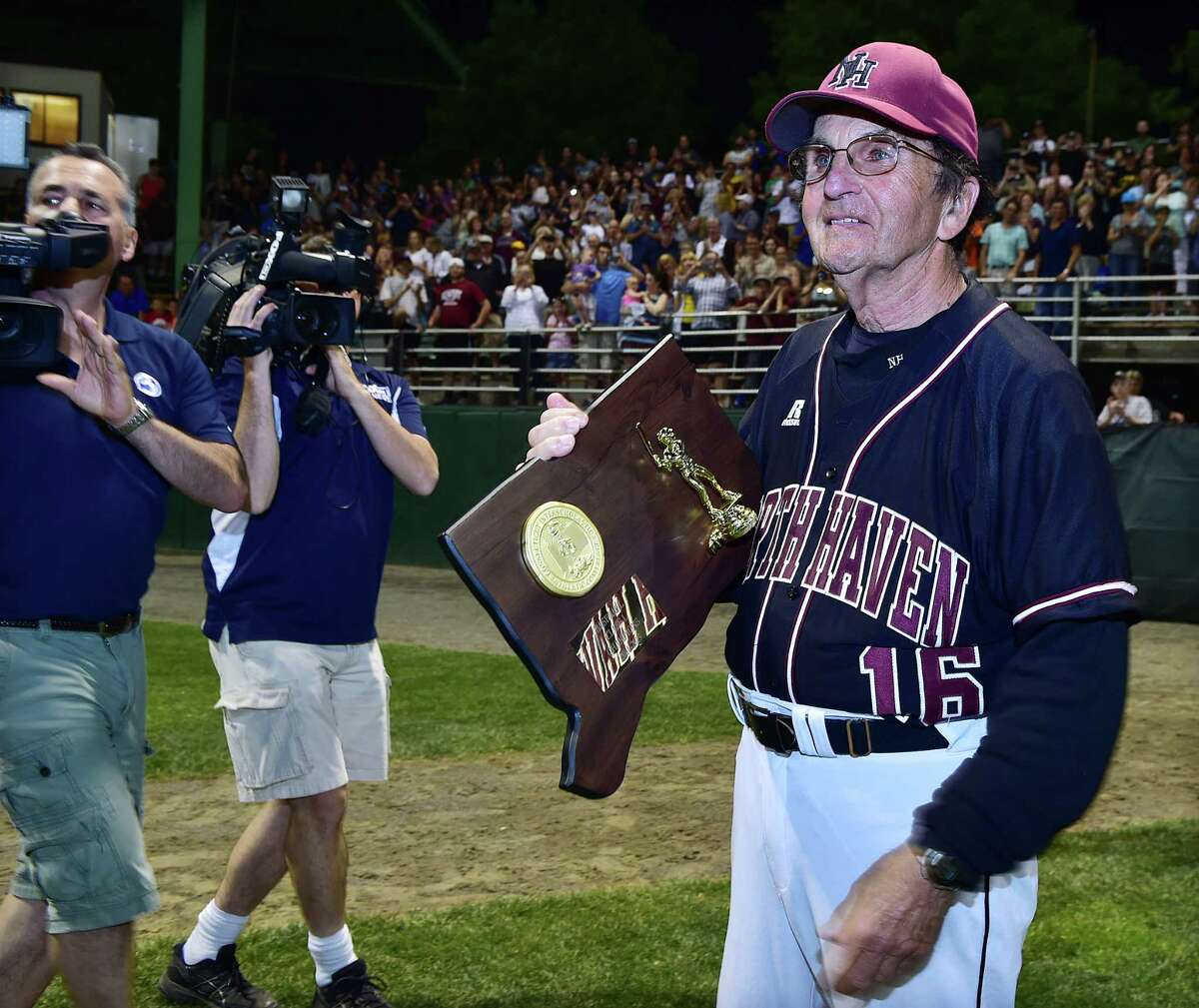 North Haven coach Bob DeMayo holds the 2015 Class L baseball championship trophy following the Indians’ 3-2 victory over East Lyme June 13, 2015 (Photo Catherine Avalone)