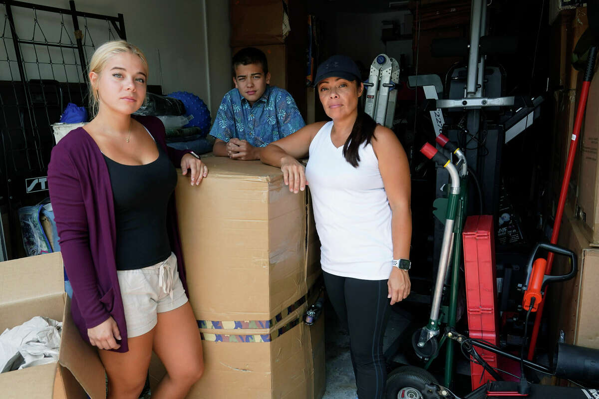 Wendy Kaufman stands at the entrance to her packed garage with her daughter Jaedyn, 19, and son Julian, 14. The Kaufman's moved from Germany and have been unable to find a home big enough that they can afford.