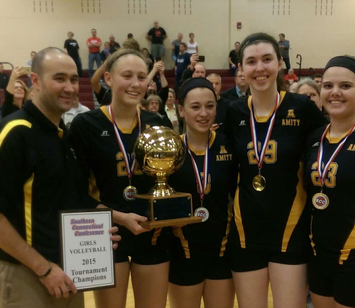 Amity coach Seth Davis, Micaela Cardozo, Cassidy Kirby, Katriana Helfenbein and Karalyn Kachmar (left to right) pose with the Southern Connecticut Conference tournament trophy after defeating Cheshire 3-2 Friday at North Haven High School.