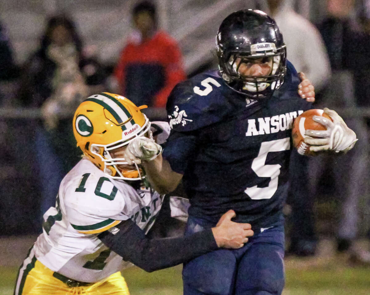 Ansonia running back Tyler Bailey (5) looks to slip from the grip of Trinity Catholic linebacker Nick Granata during Ansoina’s 31-22 win Monday evening to advance to the Class S State final.-John Vanacore/New Haven Register