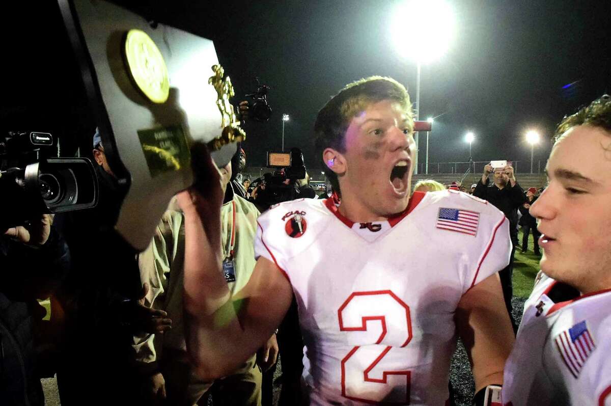 Cass Knox, who’d been injured all season, shows off the Class L championship trophy for New Canaan after a 41-35 victory over North Haven (Peter Hvizdak – New Haven Register)