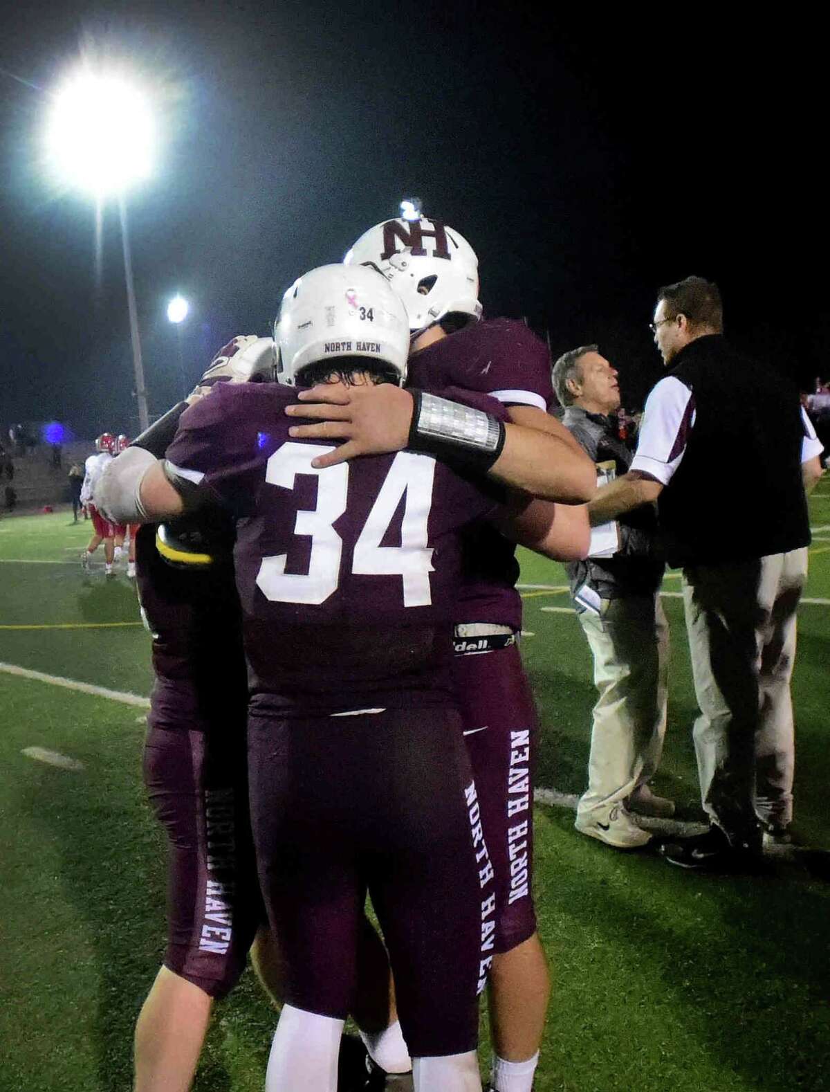 North Haven’s Conner Suraci gets a hug from his teammates after North Haven’s Class L championship loss to New Canaan. NH coach Tony Sagnella and New Canaan coach Lou Marinelli meet in the background. (Peter Hvizdak – New Haven Register)