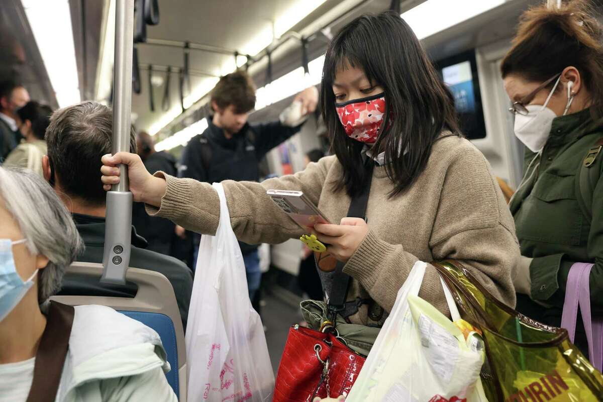 Commuters with and without masks travel on a BART train in San Francisco, Calif. State officials dropped California's masking mandate for public transit.