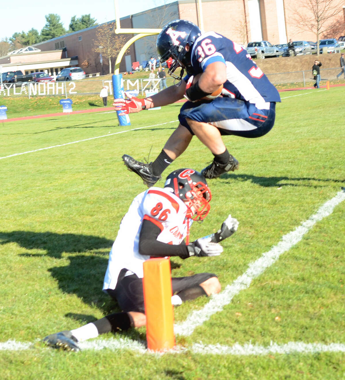 Avon’s Jimmy Murphy leaps over a Cromwell defender and into the end zone for his fourth TD of the game.