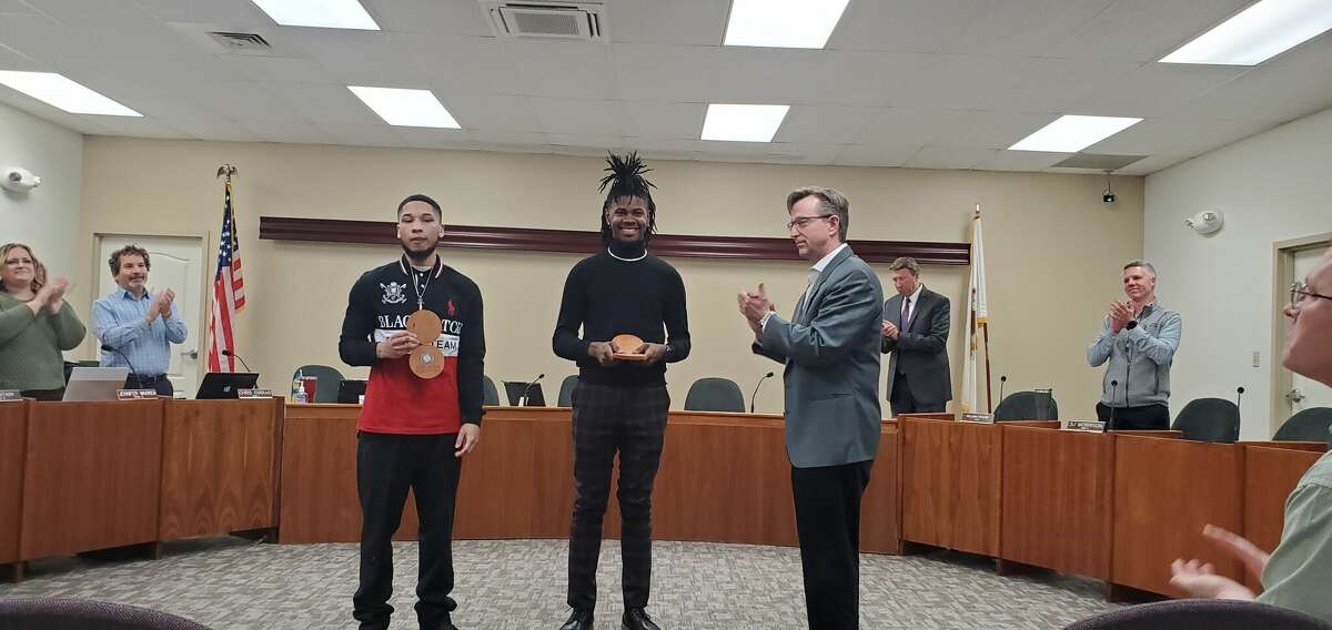 Mayor Art Risavy, right, awards two barbershop employees, Elijah Manual, center, and Kenny Howard, for their quick thinking and selfless actions in helping a woman whose car had blown a tire and she stopped in front of their shop.