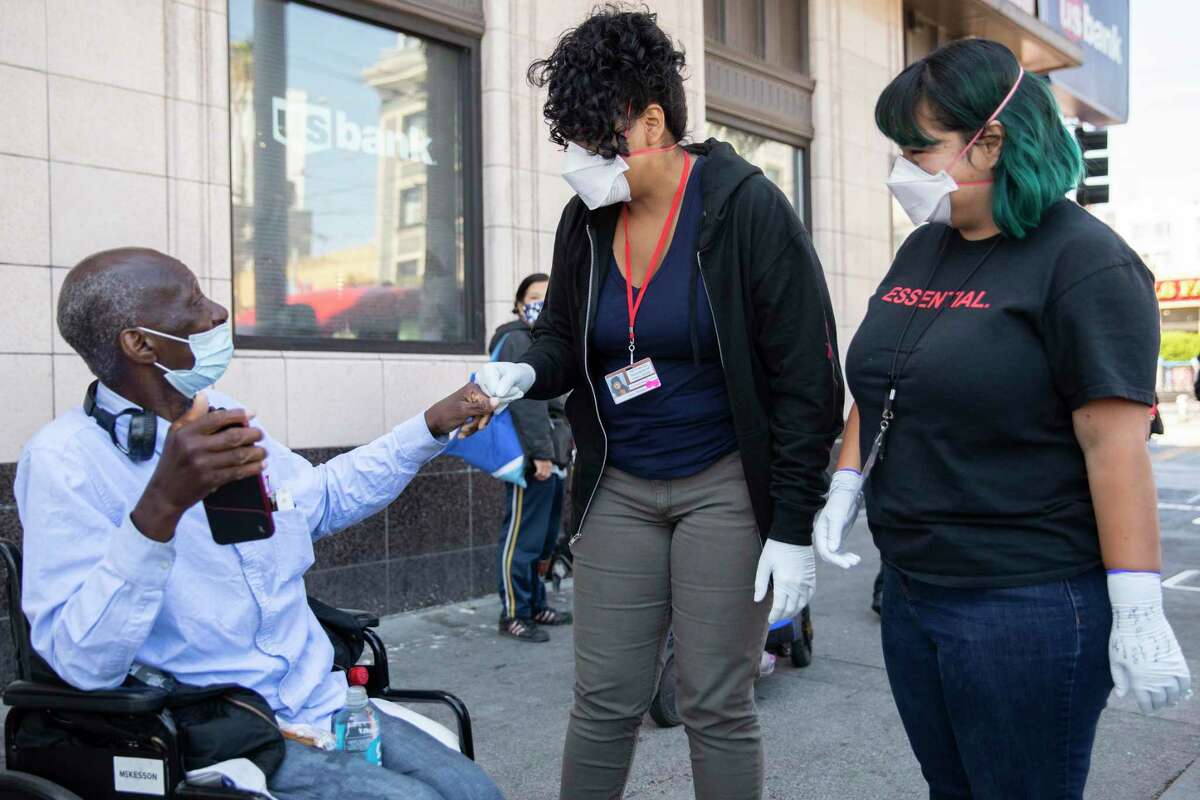Street Crisis Response Team member and clinical social worker Stephanie Chiri (right) and peer specialist Vania Mendoza talk with Paul Lumpkin, 59, after he stopped the team on the street to ask for resources near the corner of 16th and Mission streets in San Francisco on May 11.