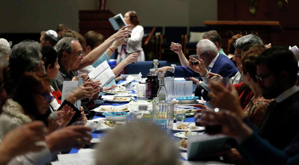 Worshippers raise their glasses of grape juice as Rabbi Annie Belford led the Passover Seder for members of her congregation along with those from Emmanuel Episcopal Church at Temple Sinai, in Houston, Saturday, April 20, 2019.