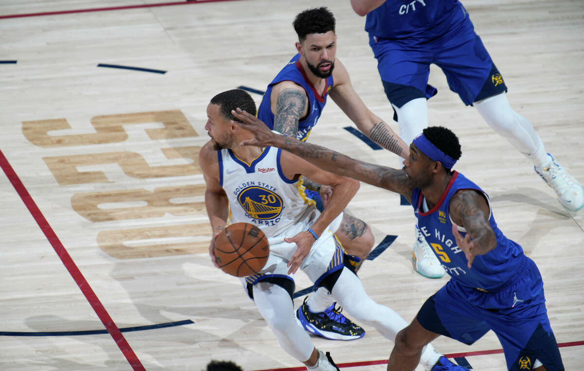 Golden State Warriors guard Stephen Curry looks to pass the ball as Denver Nuggets forward Will Barton and guard Austin Rivers defend in the first half of Game 3 of an NBA basketball first-round Western Conference playoff series Thursday, April 21, 2022, in Denver. 