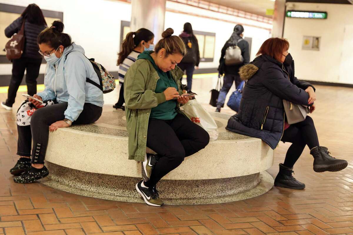 Commuters with and without masks wait at Powell Street BART station in San Francisco on April 19, 2022.