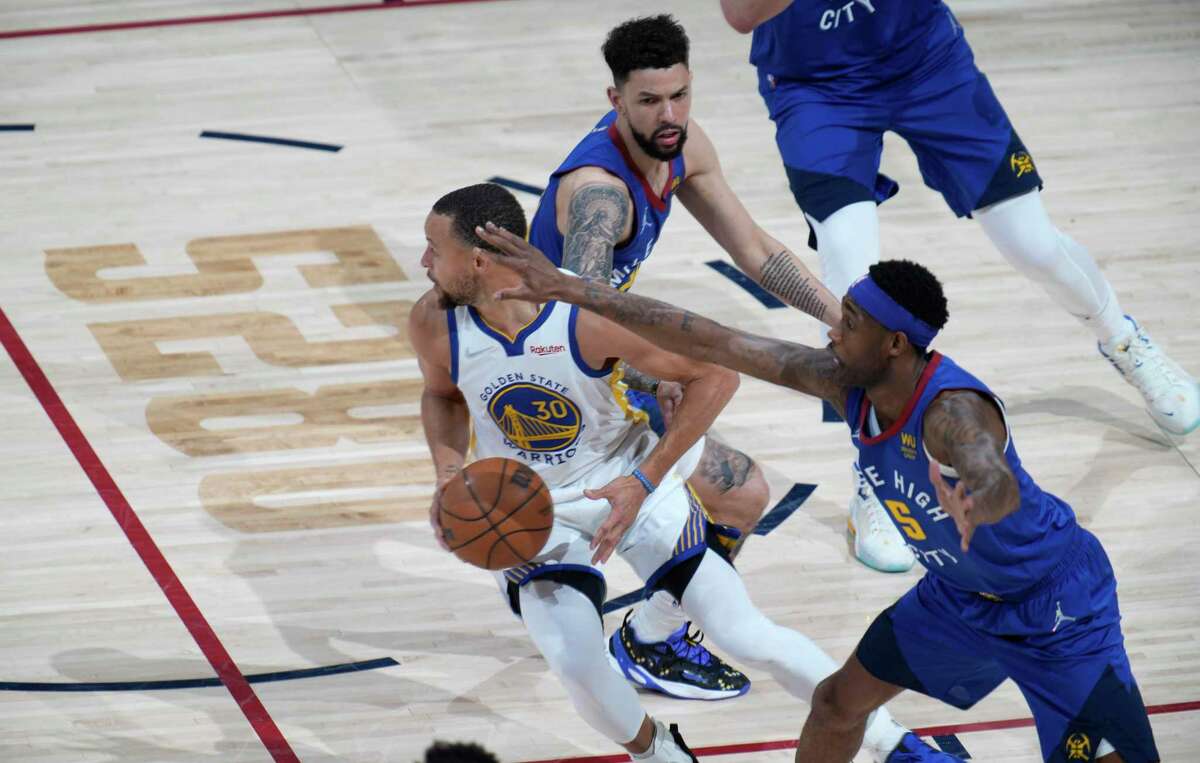 Golden State Warriors guard Stephen Curry, center, looks to pass the ball as Denver Nuggets forward Will Barton, front, and guard Austin Rivers defend in the first half of Game 3 of an NBA basketball first-round Western Conference playoff series Thursday, April 21, 2022, in Denver. (AP Photo/David Zalubowski)