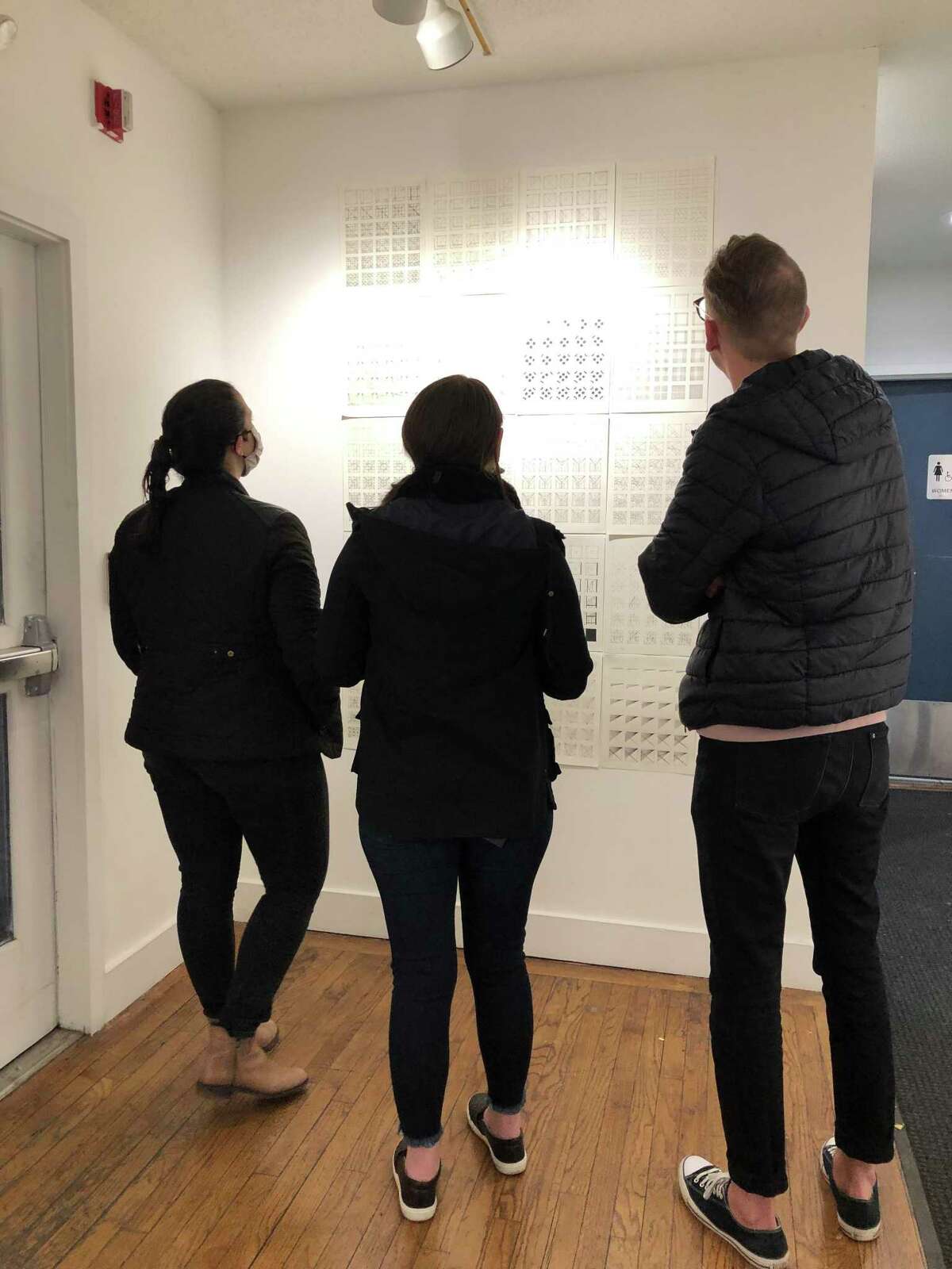 Attendees at the "Teen Fusion" show at Silvermine School of Art take in the work of a P-TECH art student. The exhibit features student artwork from the college-level graphic design class at the high school.