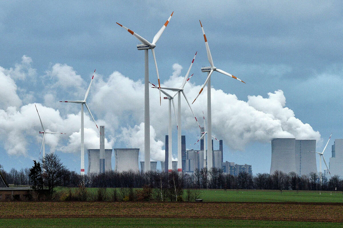 FILE - Wind turbines are seen in front of a coal fired power plant near Jackerath, Germany on Friday, Dec. 7, 2018. With climate change, plastic pollution and a potential sixth mass extinction, humanity has made some incredible messes in the world. But when people, political factions and nations have pulled together, they have also cleaned up some of those human-caused environmental problems. (AP Photo/Martin Meissner, File)