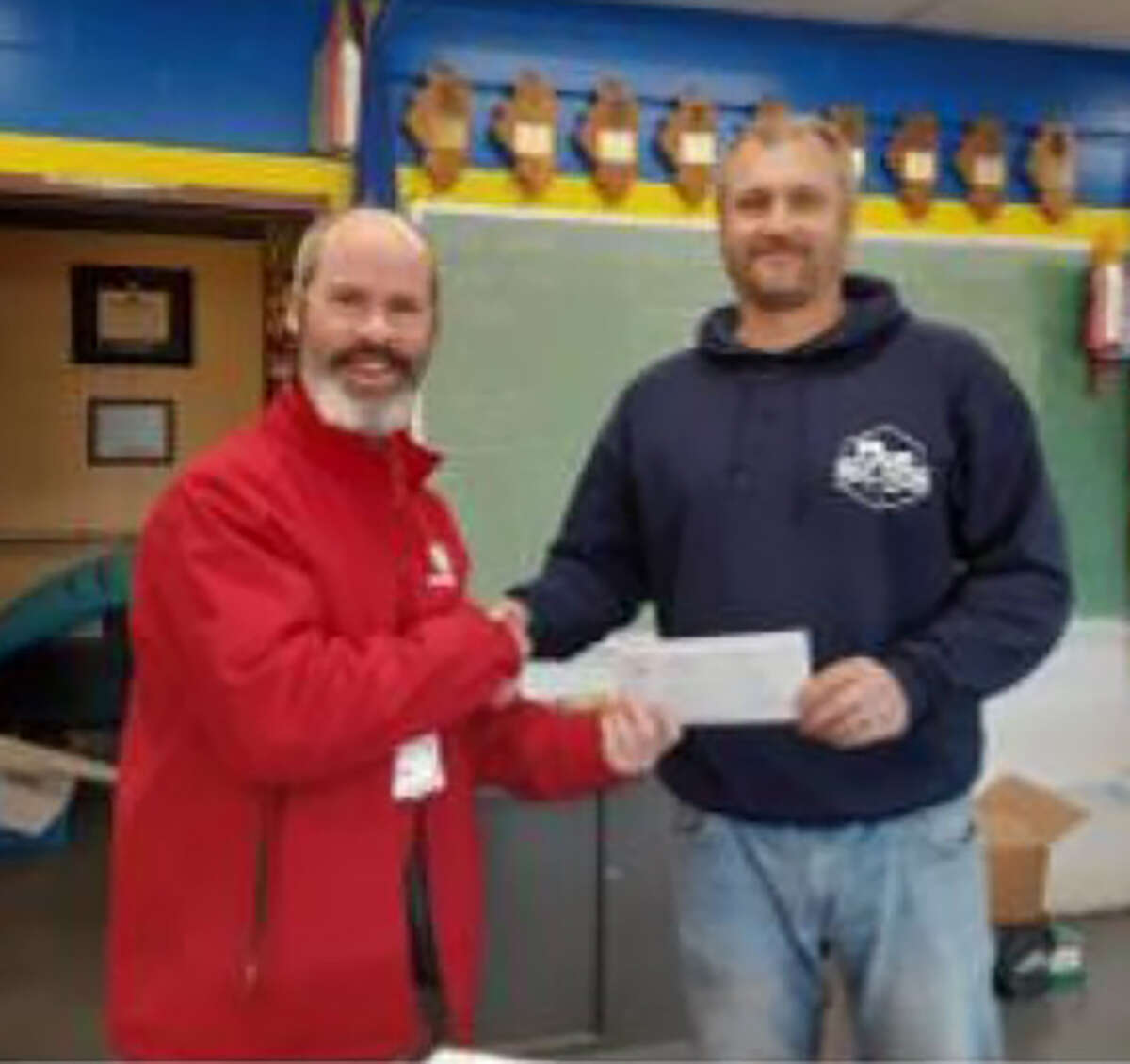 Buchheit of Jacksonville retail department manager and event coordinator Tim Weder (left) presents a check to Bryan Barnett, adviser for Winchester High School's FFA chapter. The check represented proceeds from Buchheit's annual FFA fundraiser.