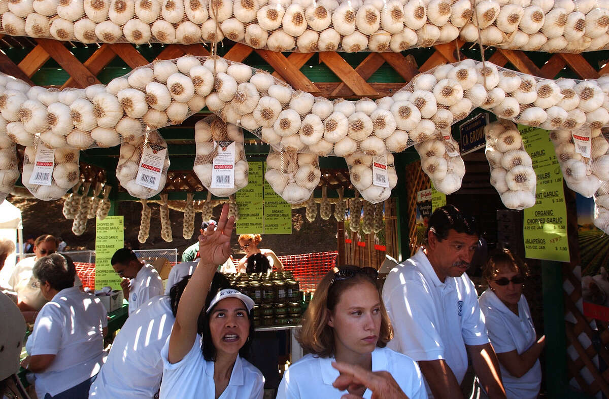 FILE — Esperanza Pineda, center left, and Jennifer Smith, center right, sell locally-grown garlic at the Gilroy Garlic Festival in Gilroy on July 24, 2004. Organizers of the Gilroy Garlic Festival announced that the longstanding event has been canceled indefinitely. 