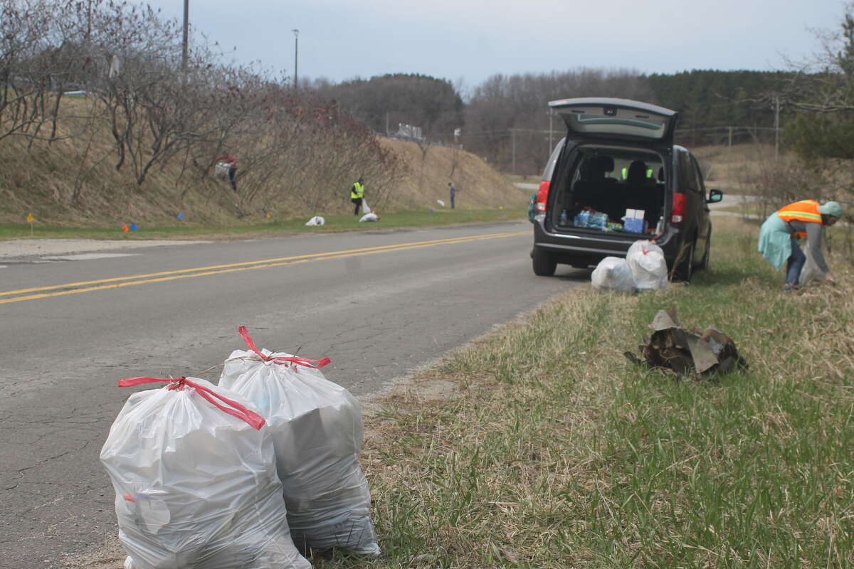 Volunteers pick up litter along Care Center Drive Friday as part of the Manistee Friendship Society's Clean the Streets event.