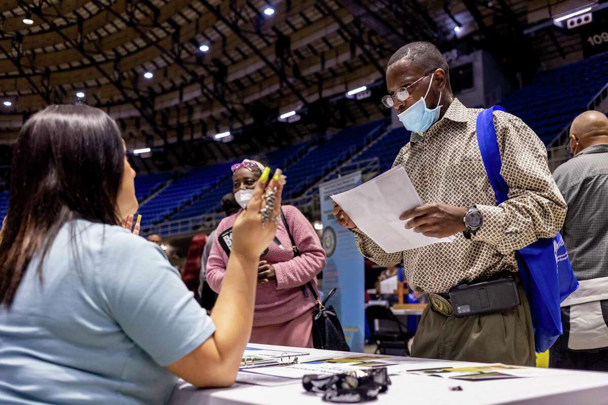 Devon Reed, right, listens to Laura Hernandez with Absolute Resourcing as she talks about job opportunities with him during the Second Chance Job Fair at Freeman Coliseum in San Antonio on Thursday.