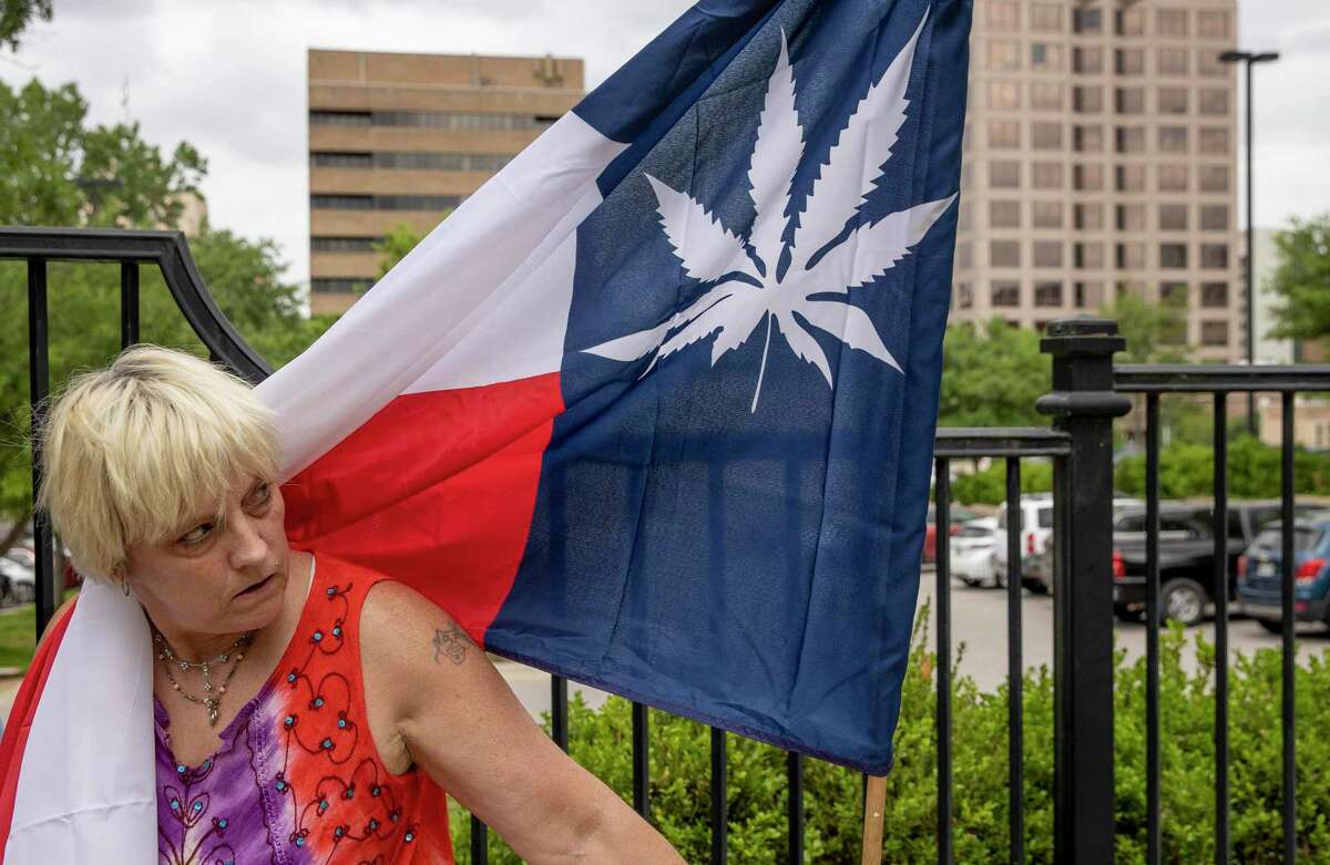 A woman holds a flag during a rally to legalize marijuana at the Governor's Mansion in Austin, Texas, on Wednesday April 20, 2022. A few dozen activists gathered at 4:20 p.m. on 4/20 to bring attention to cause. (Jay Janner/Austin American-Statesman via AP)