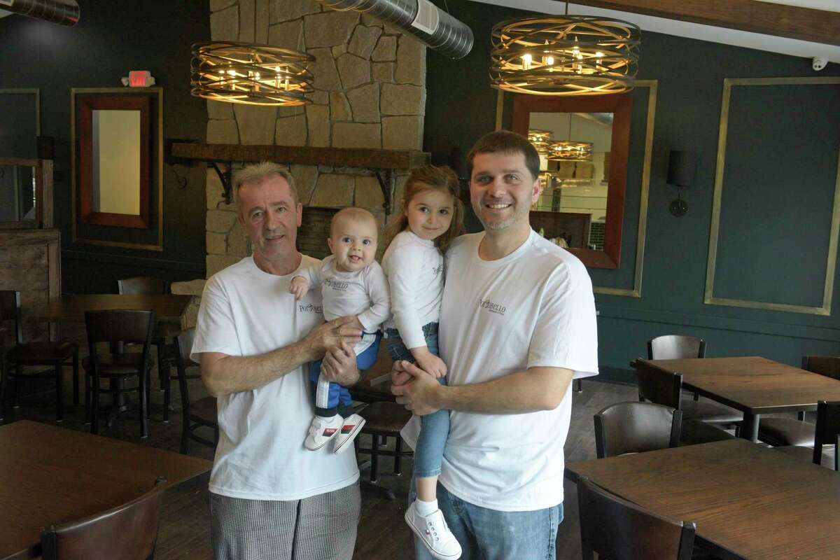 Ilir Alka, right, holding Eliza, age 3, and his father Kenny Alka holding Lirian, age 5 months, from Portobello Restaurant & Pizza which is opening at a new location in Brookfield, Conn. Tuesday, April 19, 2022.