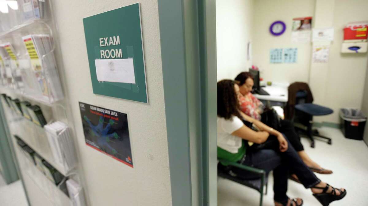 In this 2012 photo, two women wait in an exam room at Nuestra Clinica Del Valle, in San Juan, Texas. About 85 percent of those served at the clinic are uninsured. The federal government said Friday it would stop fighting a Trump-era agreement to extend a health care program that Texas uses to help pay for health care for uninsured Texans.