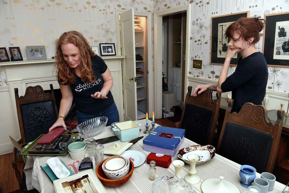 Lauren Hass, left, owner of Clutter Kicker, works with Laura Sundstrom to organize the dining room at Sundstrom’s home in New Haven.