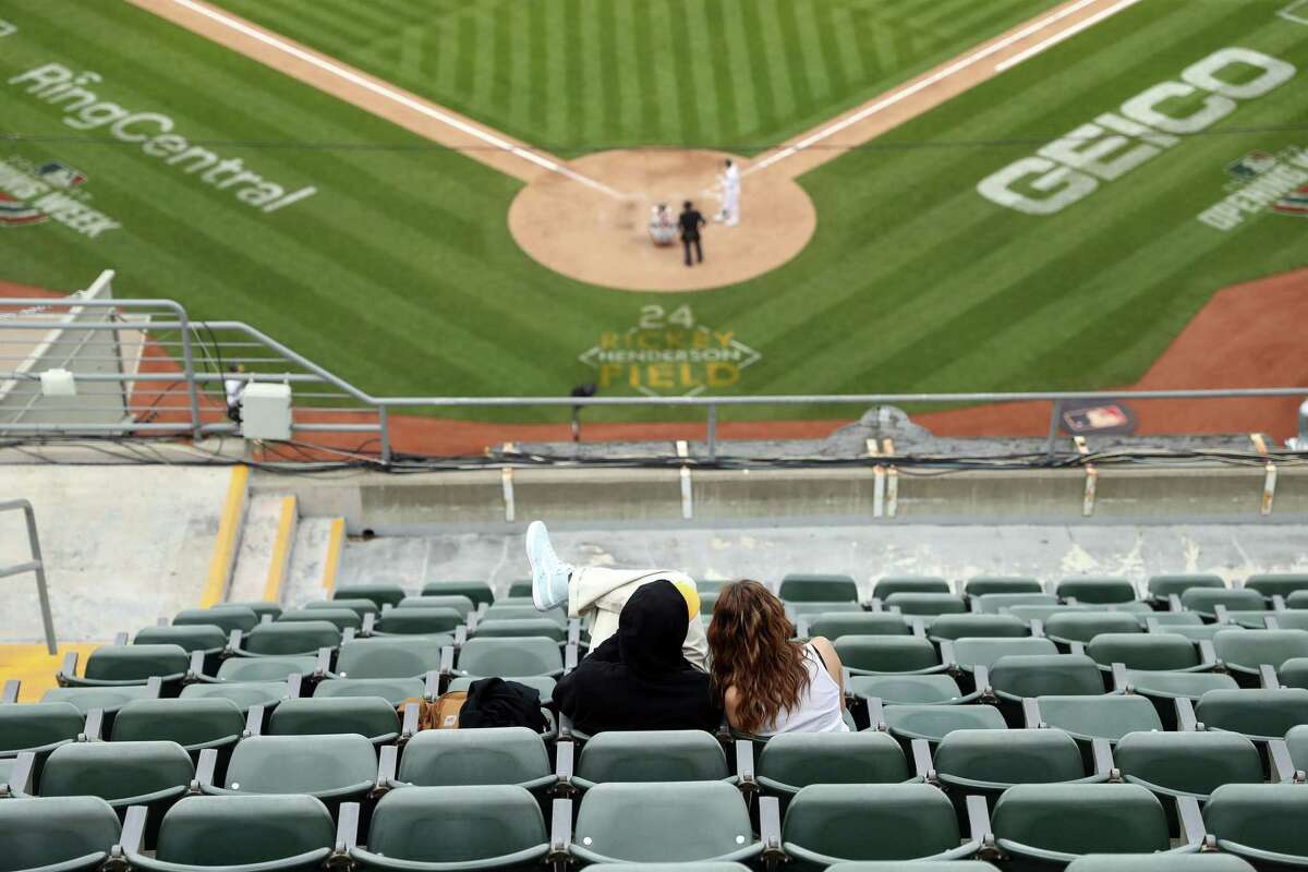 20 Nisan 2022 Çarşamba günü Oakland, Kaliforniya'daki Oakland Coliseum'daki MLB maçı sırasında Oakland Athletics, birkaç bin taraftarın önünde Baltimore Orioles ile oynarken, bir çift, çoğunlukla boş bir üst güverteden aksiyonu izliyor.