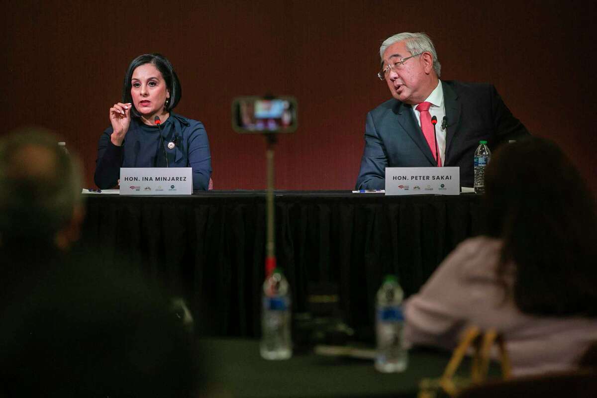 State Rep. Ina Minjarez, left, speaks as former District Judge Peter Sakai listens during a forum sponsored by local business groups at IBC Bank in San Antonio on Friday. Minjarez and Sakai are the two Democratic candidates in a May 24 runoff to succeed Nelson Wolff as Bexar County judge.